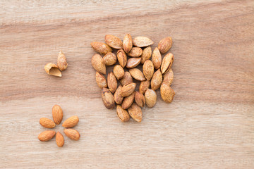 Almonds in yellow bowl on wooden background