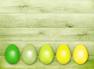 Grün-gelbe Ostereier auf Holzwand