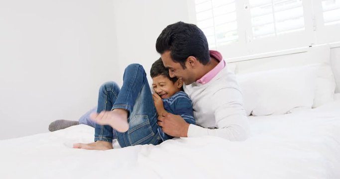 Father and son playing on bed