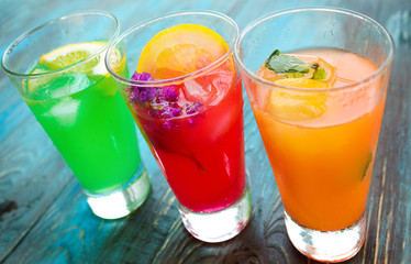 Different kinds of fresh lemonades in glasses on wooden background
