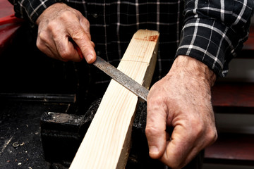 old man hand planers wood in the workshop