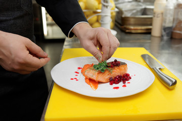 Chef is decorating fried salmon steak with herbs
