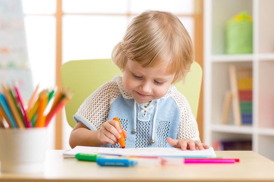 Cute child boy is drawing with felt-tip pen in preschool