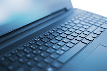 Modern black laptop keyboard from curved angle with blurred sides 