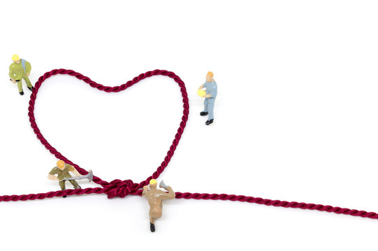 Miniature worker team building Heart Shaped with rope on white background .