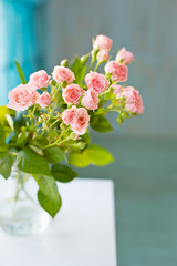 Little rose flowers on a white wooden table