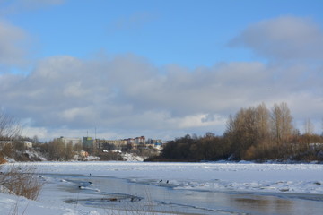 beautiful winter landscape: a city  in the distance, blue sky, river and snow, nature 