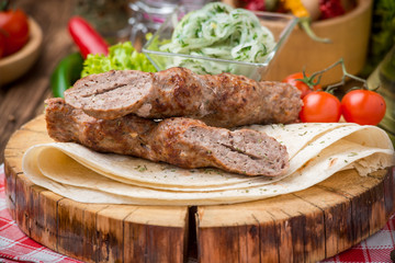 grilled beef meat on the grill kebab on pita bread and a wooden plate