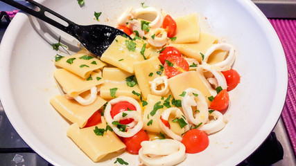 Paccheri, Italian pasta with squid sauce, small tomatoes, garlic, chili, parsley, and grated lemon