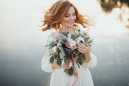 Beautiful bride with bouquet on stylish background of the river. Rustic style
