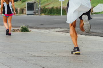 Man runs on a sidewalk doing exercise next to a street