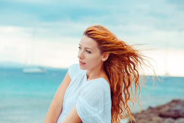 Side profile portrait of young serious thoughtful woman standing by the ocean