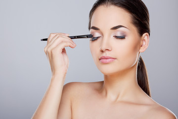 Fototapeta premium Girl painting eyelids with eye shadows
