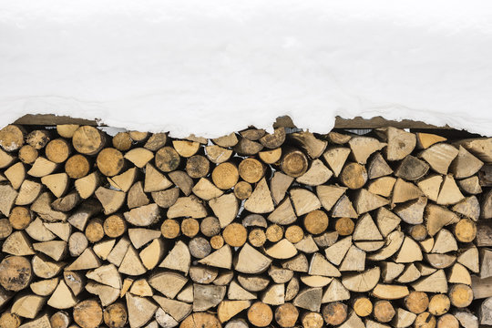 Firewood Logs Covered with Snow. Winter Texture Pattern Background.