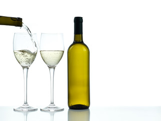 Bottle and glasses of white wine on a white background. Wine poured in one glass from a bottle.
