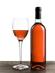 Bottle and glass of rose wine on a wooden table and a white background