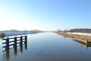 Fototapeta na wymiar het zonnetje schijnt op een winterdag op een besneeuwde rivier de Oude IJssel bij Hoog Keppel