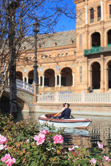 Obraz premium Roses and blurred touristic boat with loving couple, Spain square, Seville, Spain 