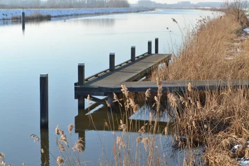 Fototapeten aanlegsteiger voor kleine bootjes in de winterse rivier de Oude IJssel © henkbouwers