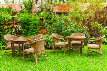 Wodd table and chairs standing on a lawn in garden.