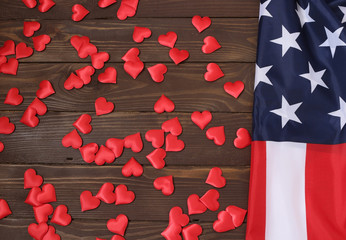 Bulk red hearts and USA flag, on a wooden table. view from the top. Celebration, love, patriotism...