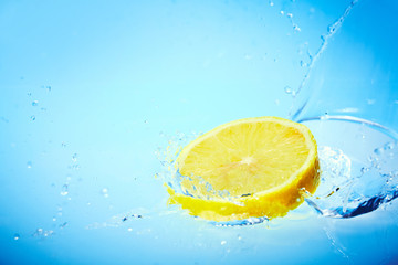 Fetta di limone cade nell'acqua con splash fondo blu