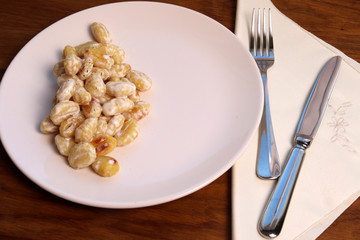 Gnocchi with cream and spices on a white plate. Homemade food. Italian rustic food.