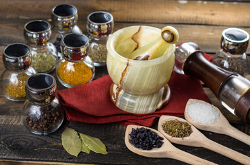spices in spoons and Jar with mortar on wodeen background
