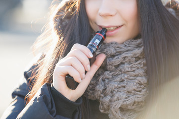 Young white girl vaping outdoor in winter