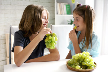 happy couple of teenagers eating grapes