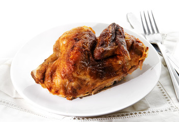 grilled half chicken served on a plate, background fades to white