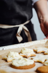 Person putting a cream with the spoon to the cookies.