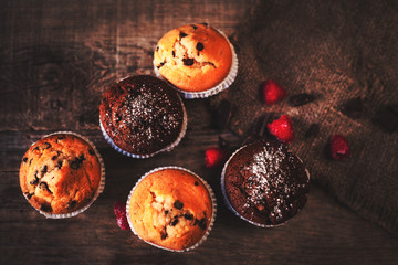 Fototapeta na wymiar Chocolate dark muffins on wooden background with powdered sugar
