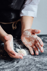 Hands of person picking odd flour on kitchen table. Vertical studio shot. 