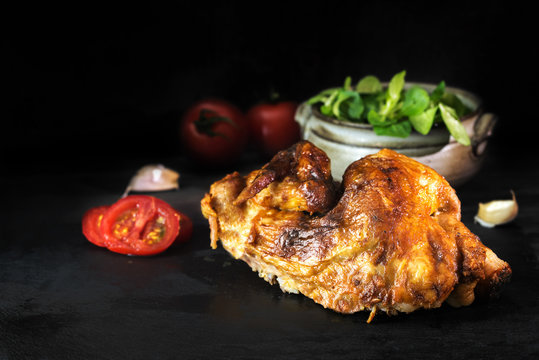 grilled half chicken on a dark slate plate with salad and tomatoes, copy space