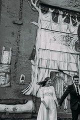 Newlyweds embracing next to graffiti wall. Young wedding couple.