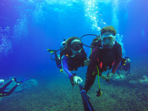 Underwater couple scuba diving selfie shot with selfie stick. Deep blue sea. Wide angle shot.