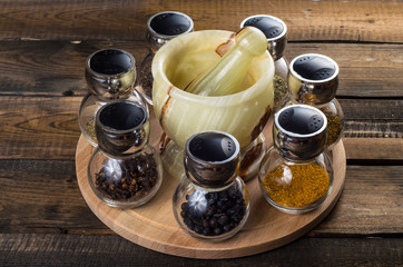 spices in spoons and Jar with mortar on wodeen background