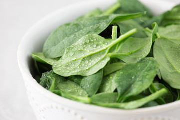 Washed fresh mini spinach in a plate on an stone background