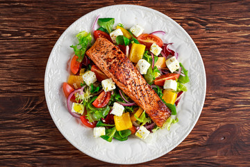 Fried Salmon steak with fresh vegetables salad, feta cheese. concept healthy food.