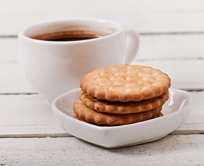 Cup of coffee and delicious baked cookies on old wooden background.