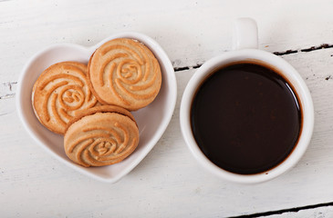 Cup of coffee and delicious baked cookies on old wooden background.