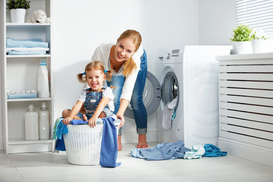 family mother and child girl  in laundry room near washing machi