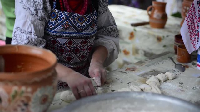 The process of preparation of Ukrainian traditional bakery products - dumplings. Women's hands knead the dough. Rustic style.
