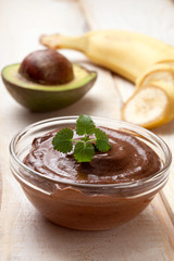 raw vegan pudding with avocado and banana on a light wooden background