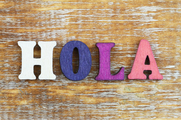 Word hola (hello in Spanish) written with colorful letters on wooden surface   © graletta
