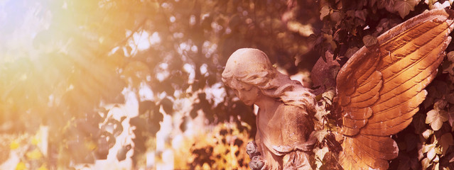 Vintage image of a sad angel on a cemetery against the backgroun