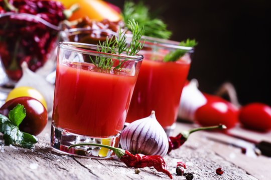 Spicy tomato juice with vegetables on a vintage wooden backgroun