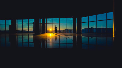 The man stand in a skyscraper business center windows on a background of sunset
