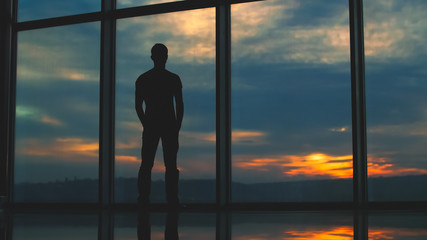 Fototapeta na wymiar The man stand near the window on the background of sunset